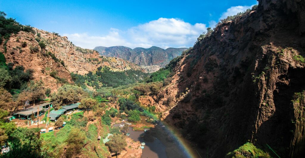 Beautiful canyon landscape with river and rainbow under clear blue sky, perfect for summer travel imagery.