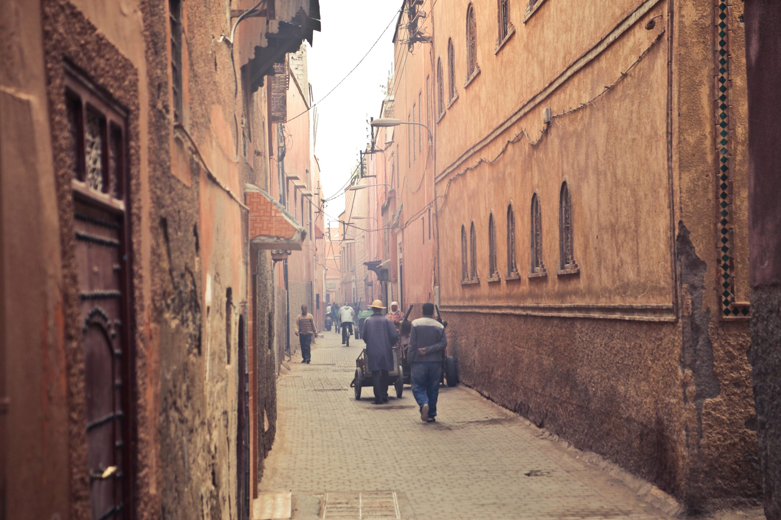 Perspective view of aged narrow street with people walking among ancient oriental buildings in hazy light